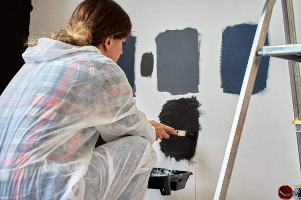 Person wearing protective gear, painting swatches to see if the blue paint dries darker or lighter near Warwick, RI